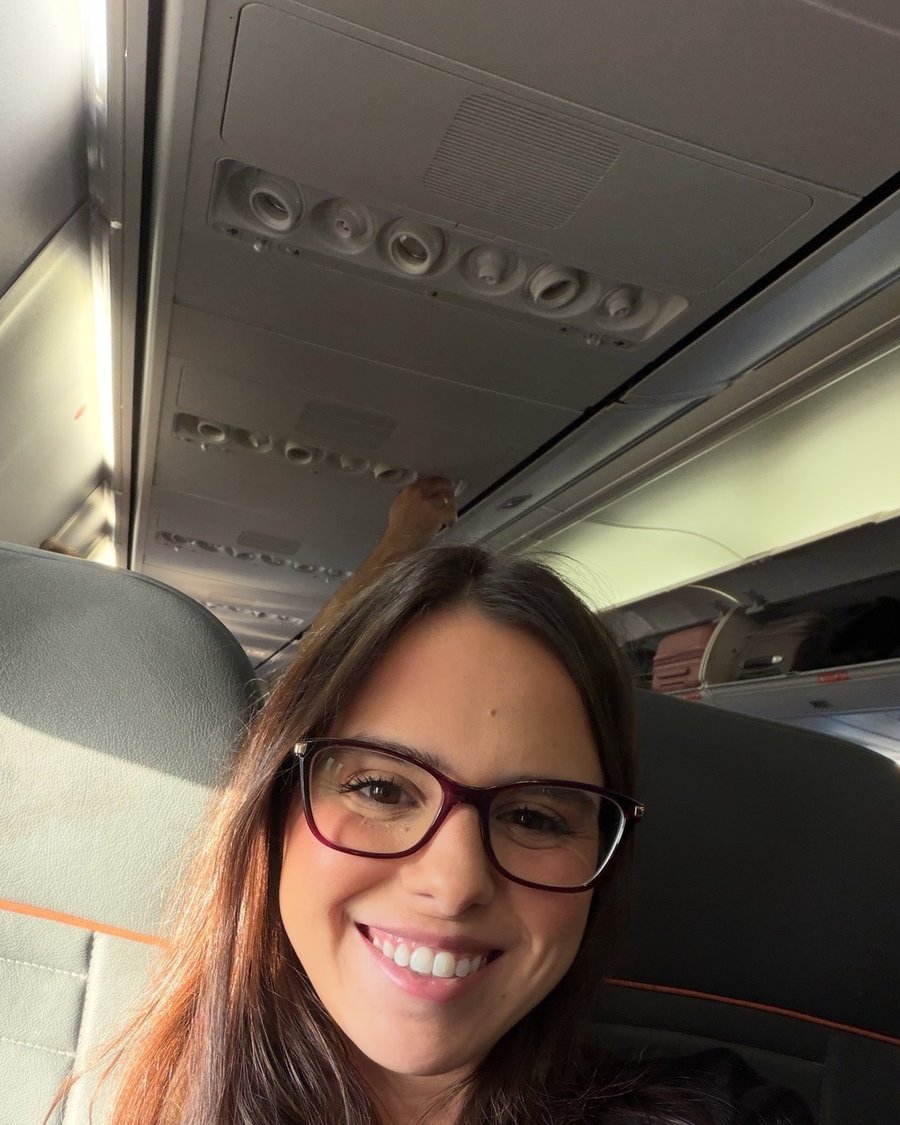 Nathalia sorrindo na poltrona do avião